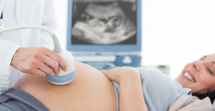 doctor performing ultrasound on a pregnant woman's abdomen